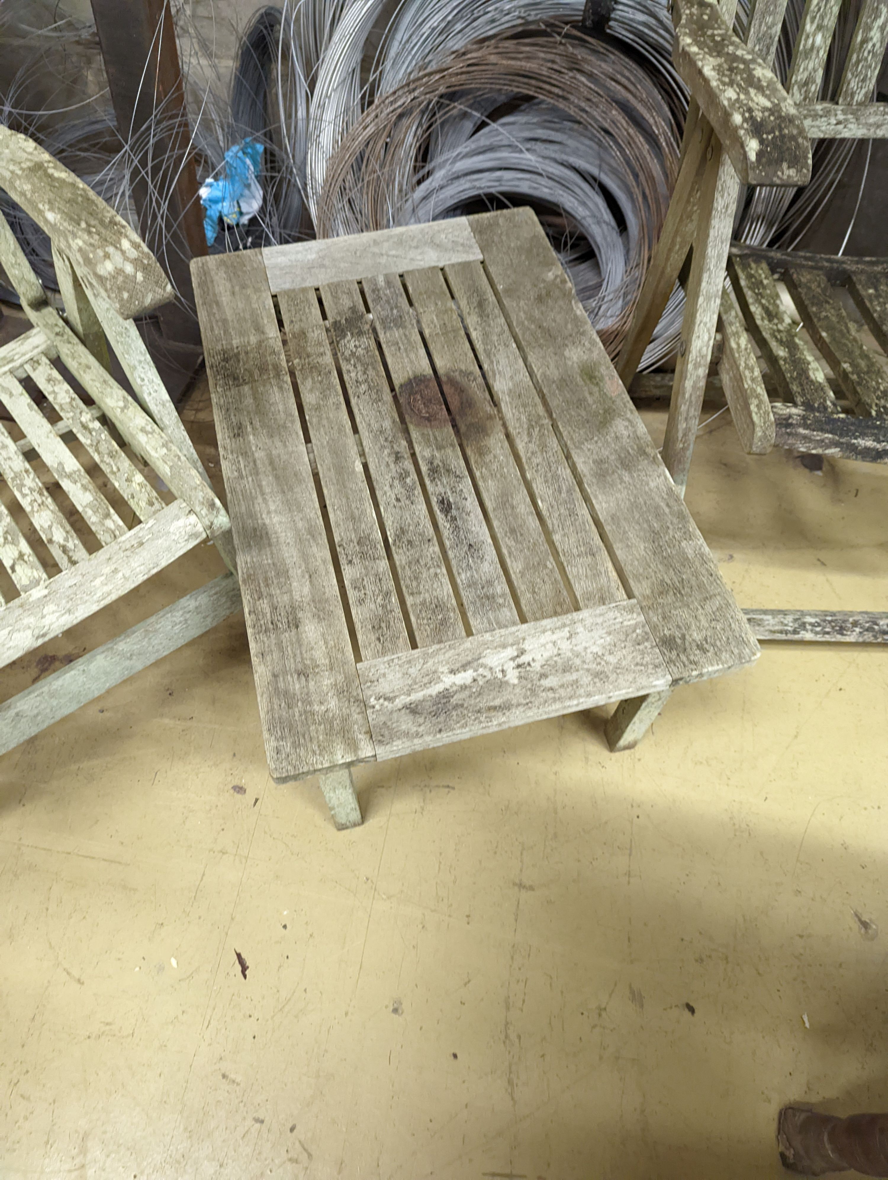 Two weathered teak folding garden armchairs and a low table